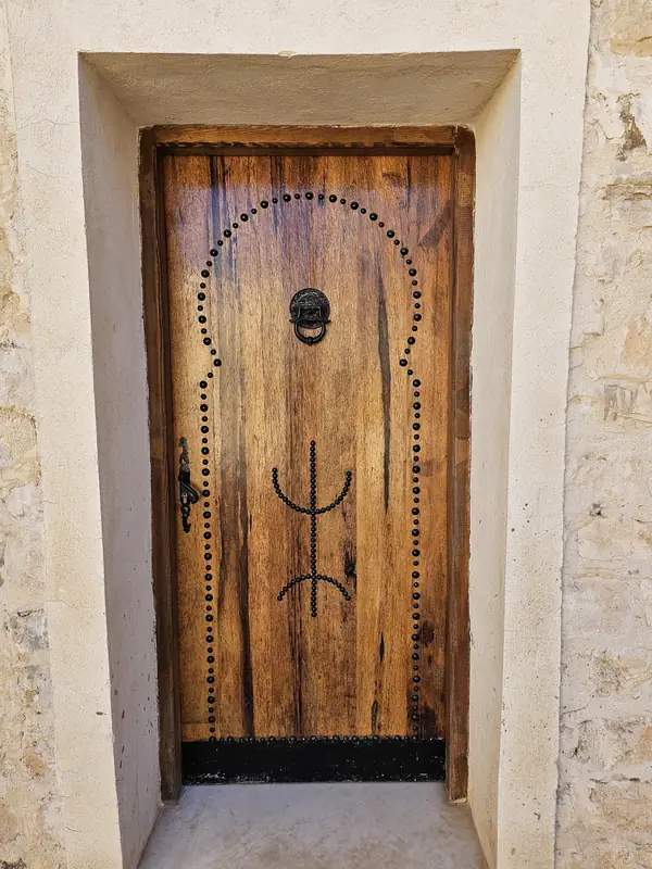 Porte en bois clouté ornée d'un symbole amazigh à Dar Zmen