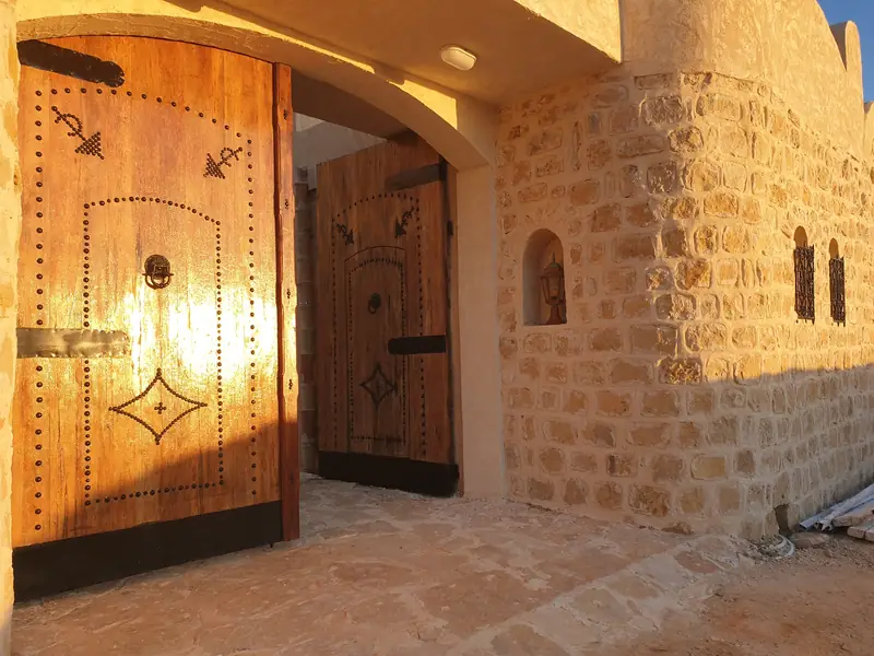 Les portes en bois clouté de l'entrée de Dar Zmen au soleil couchant